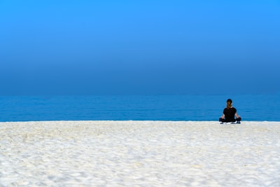 Women who dress in black shirt sitting on a white beach during the day
